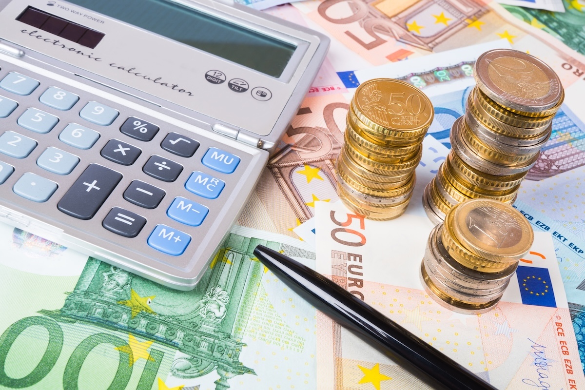 Soldi, calcolatrice e penna per fare i conti