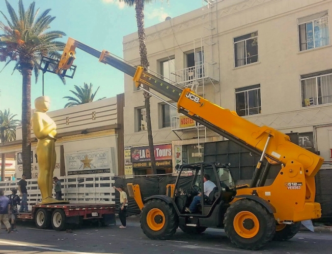 Il sollevatore Jcb  movimenta la statua dell'Oscar da 7 metri